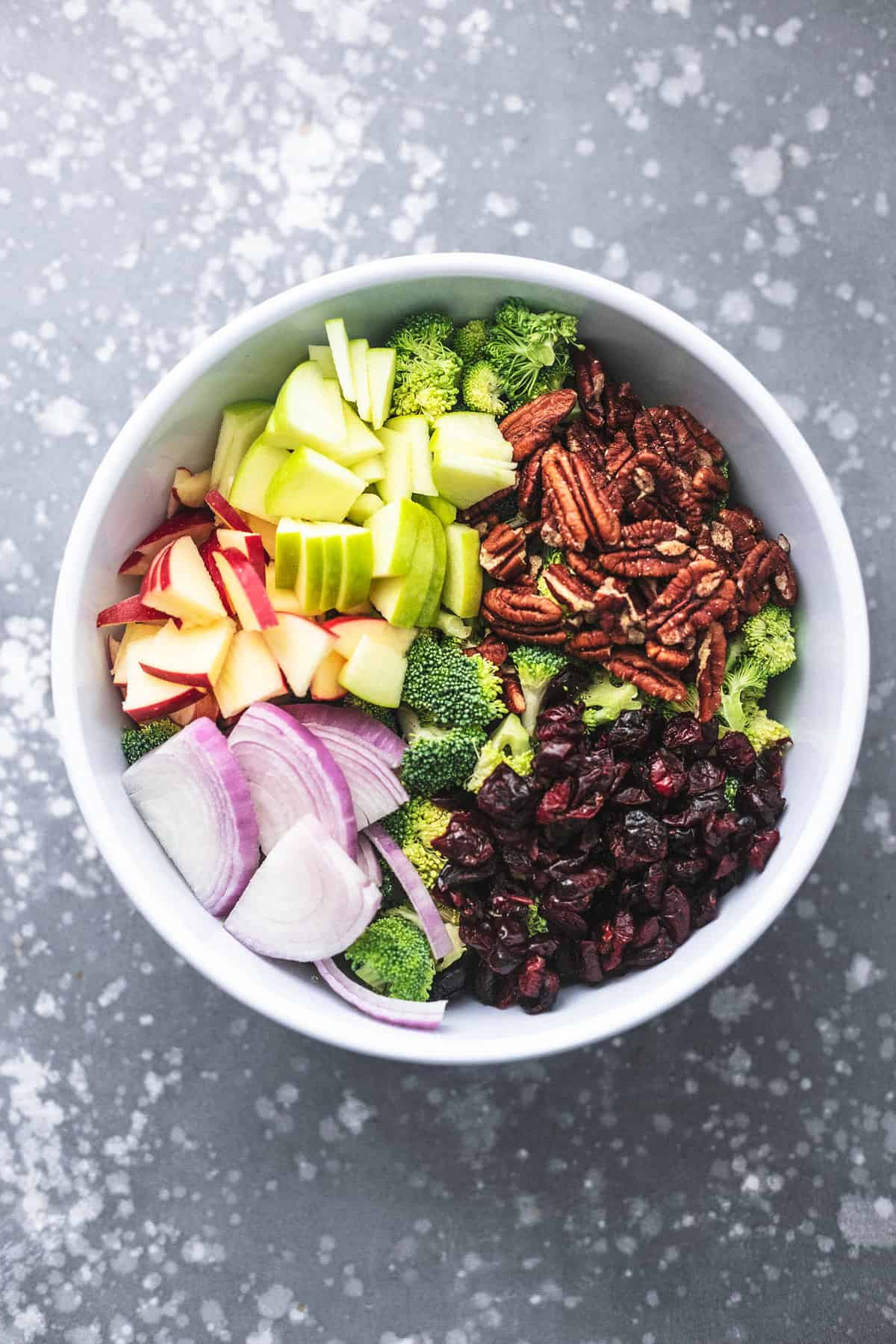 top view of broccoli apple salad ingredients in a bowl.