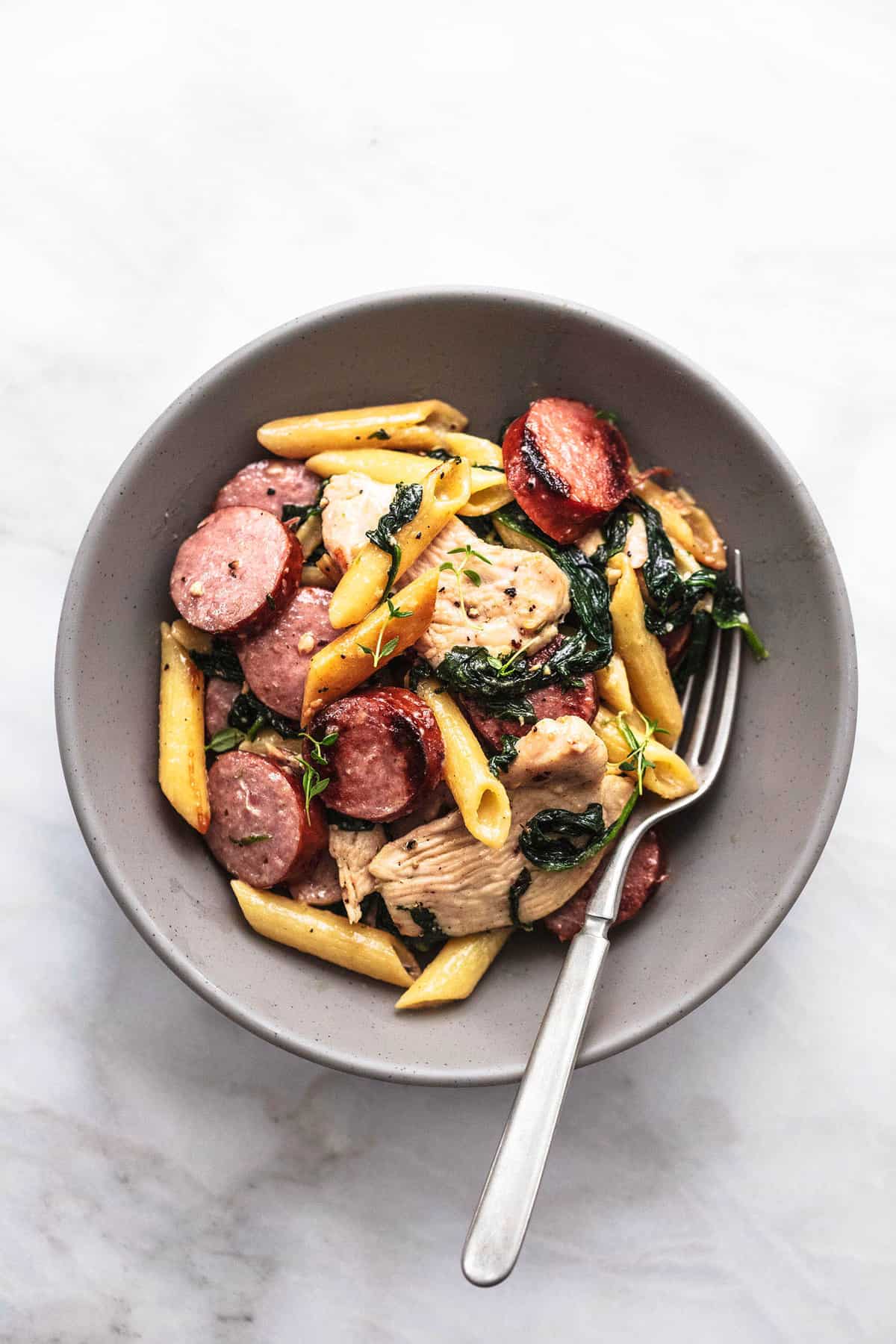 top view of chicken and sausage pasta with a fork in a bowl.