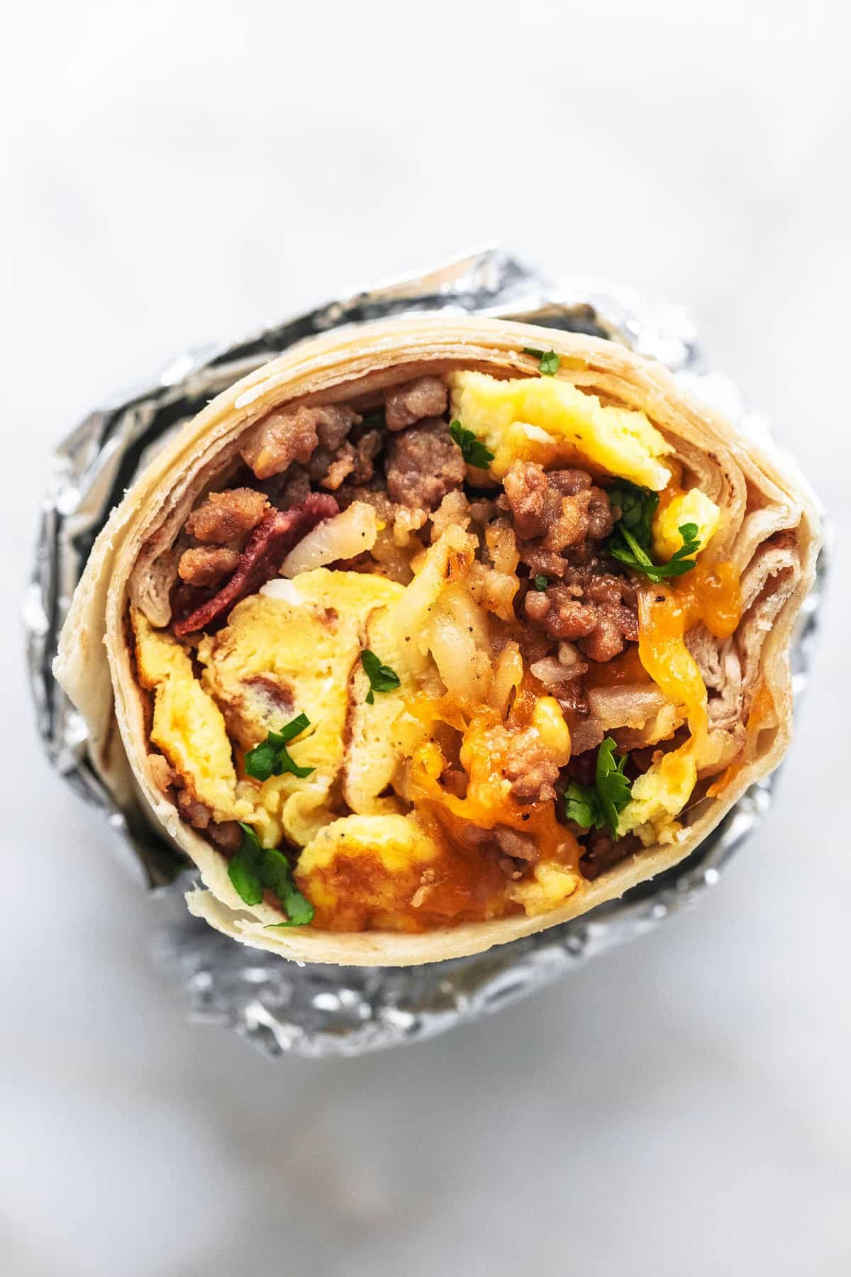 top view of a freezer breakfast burrito standing up partly wrapped in foil.