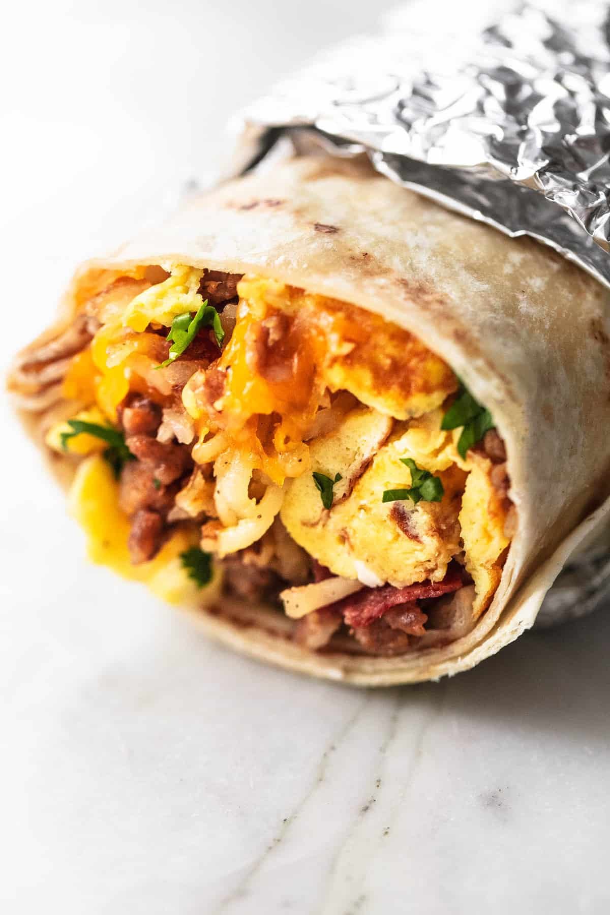 a freezer breakfast burrito partly wrapped in foil.