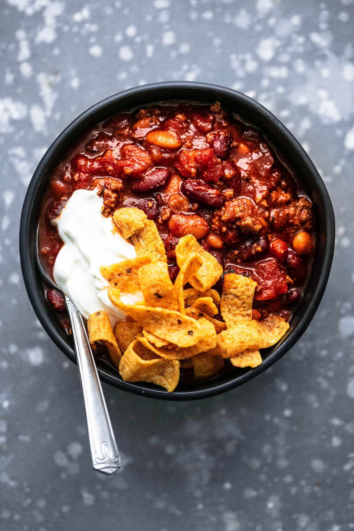 top view of instant pot chili with Fritos, sour cream and a spoon in a bowl.