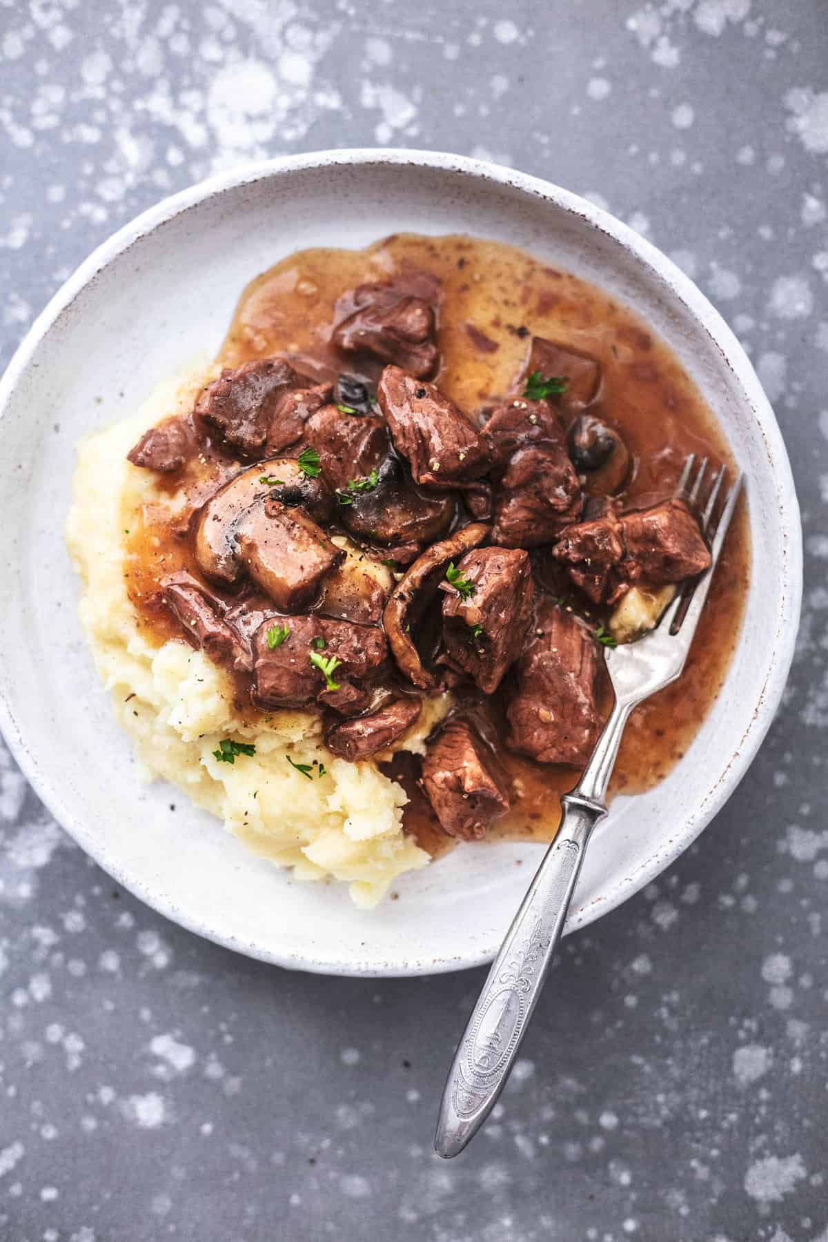 top view of instant pot beef tips with mashed potatoes and a fork on a plate.