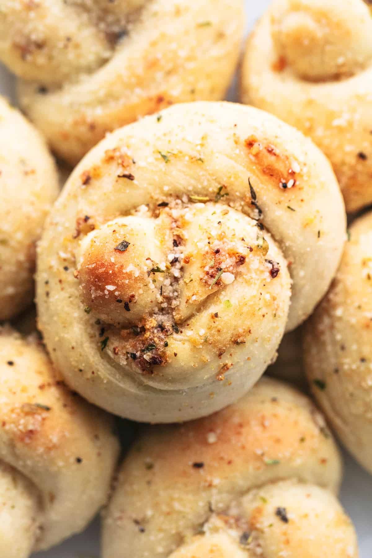 close up top view of a homemade garlic parmesan knot surrounded by more knots.