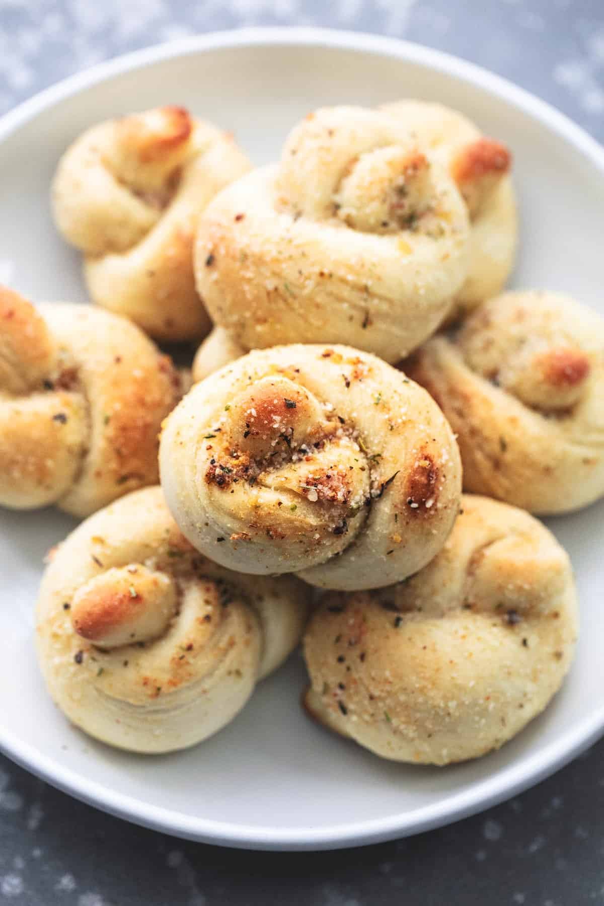 close up of homemade garlic parmesan knots on a plate.