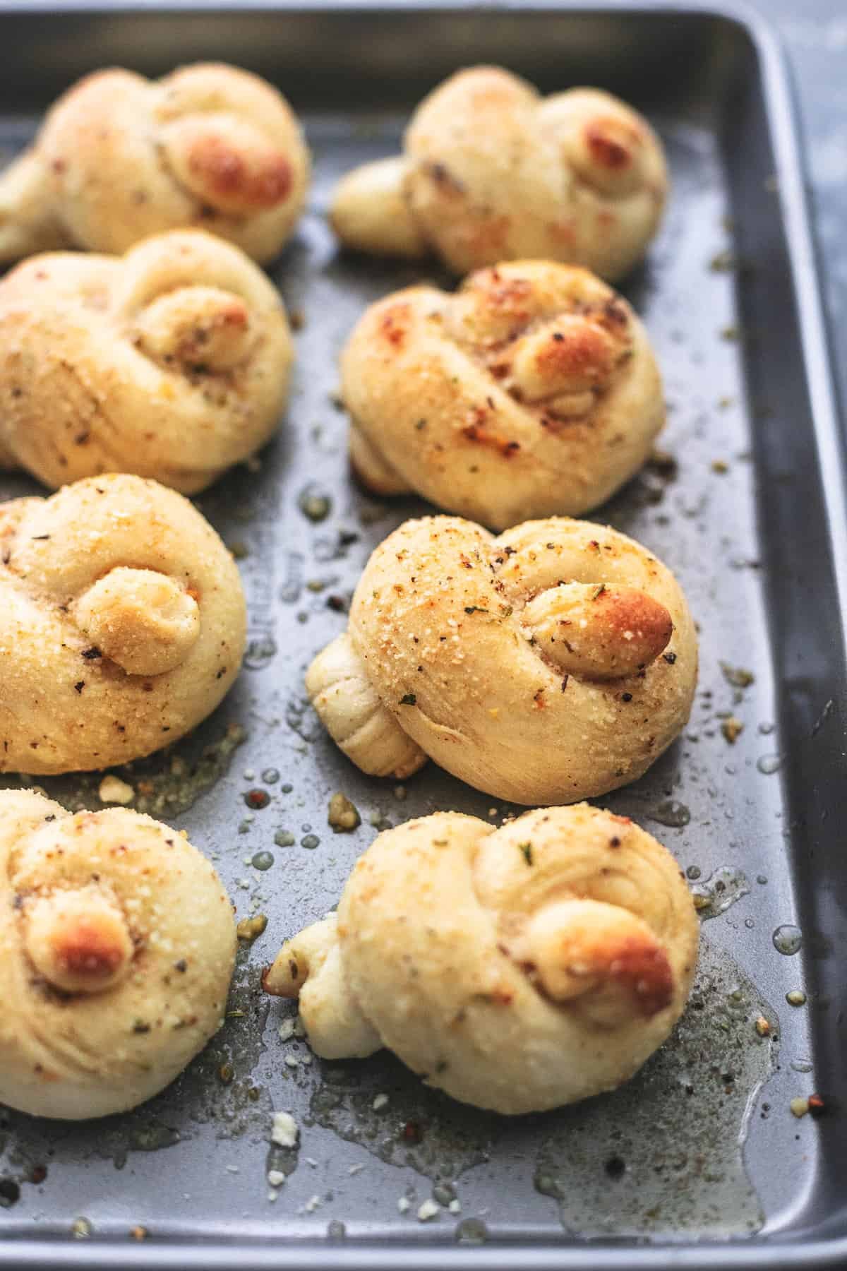 close up of homemade garlic parmesan knots on a baking sheet.