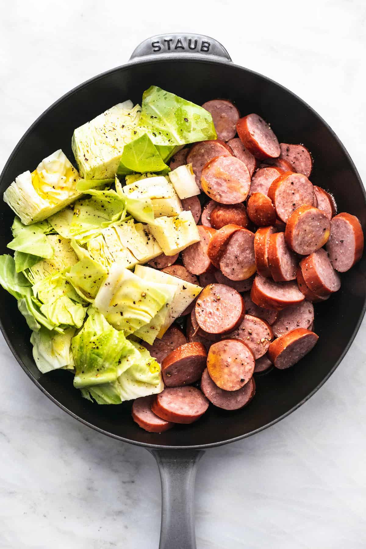 top view of cabbage and sausage in a skillet.