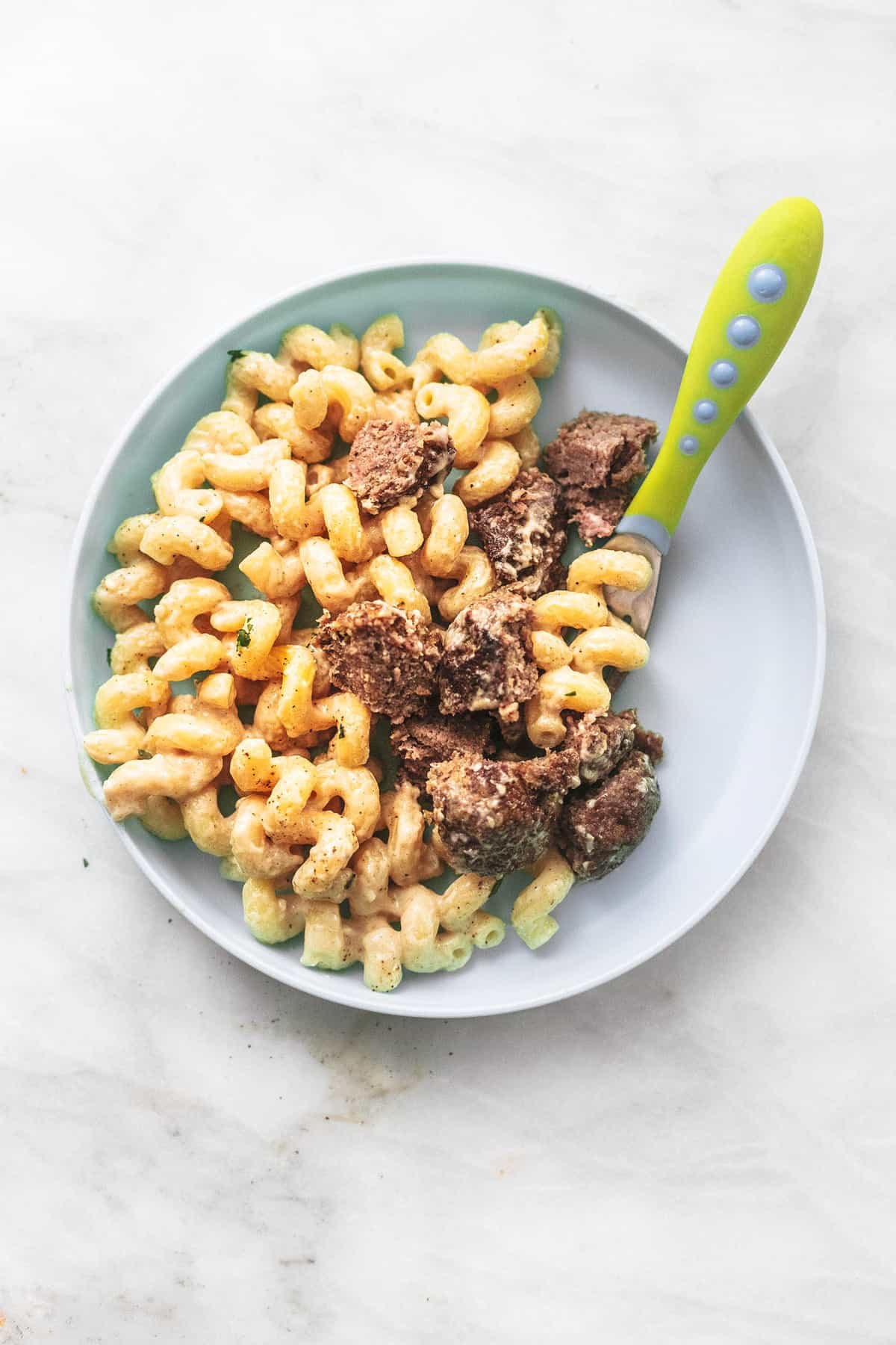 top view of Swedish meatball pasta with the meatballs cut up into bites with a baby fork on a plate.