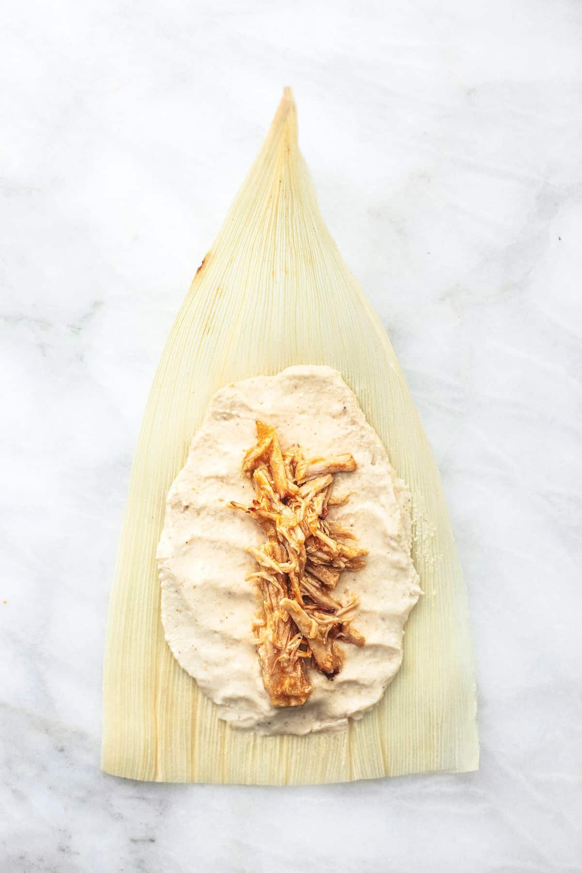 top view of an opened unmade tamale on a corn husk.