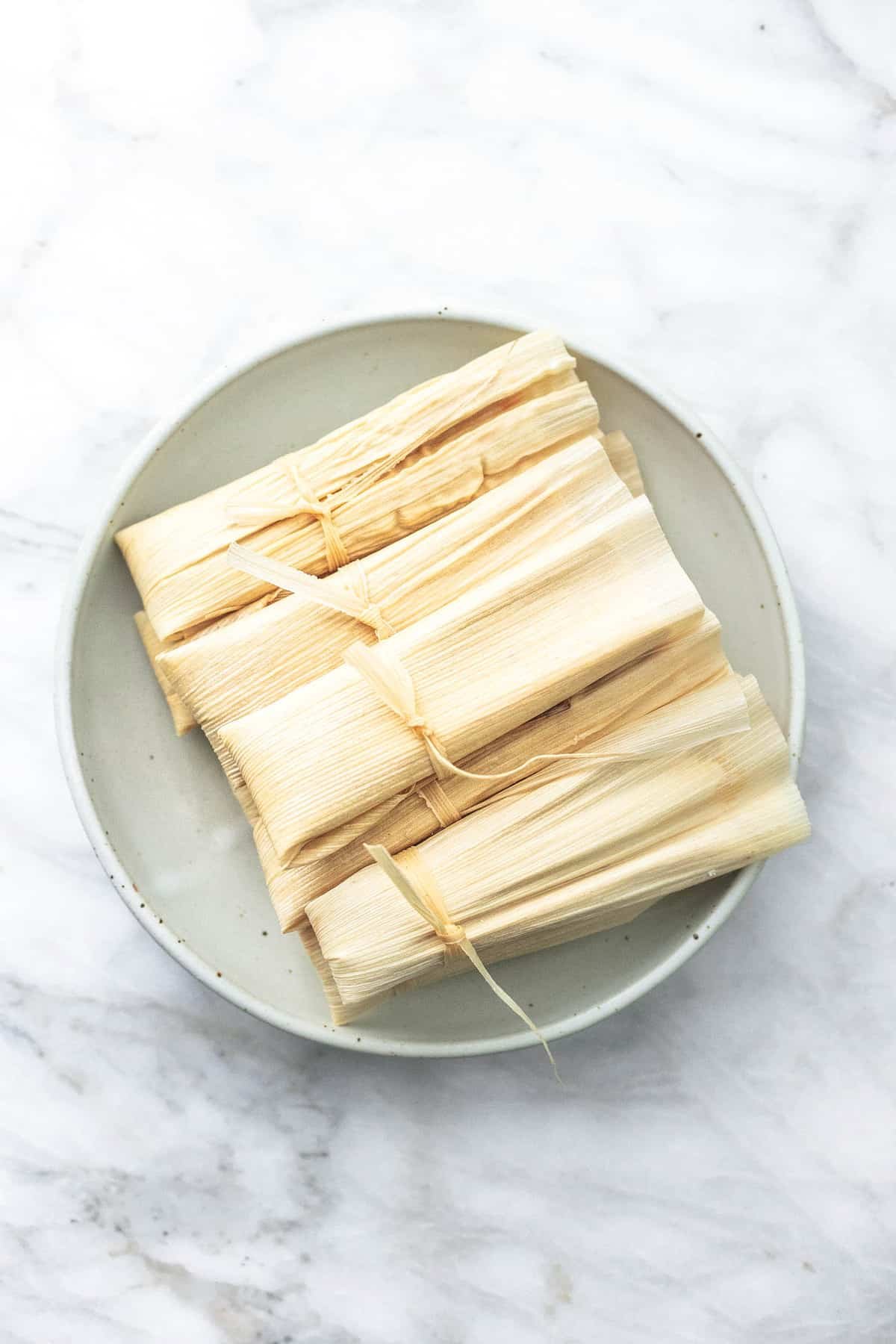 top view of wrapped tamales on a plate.