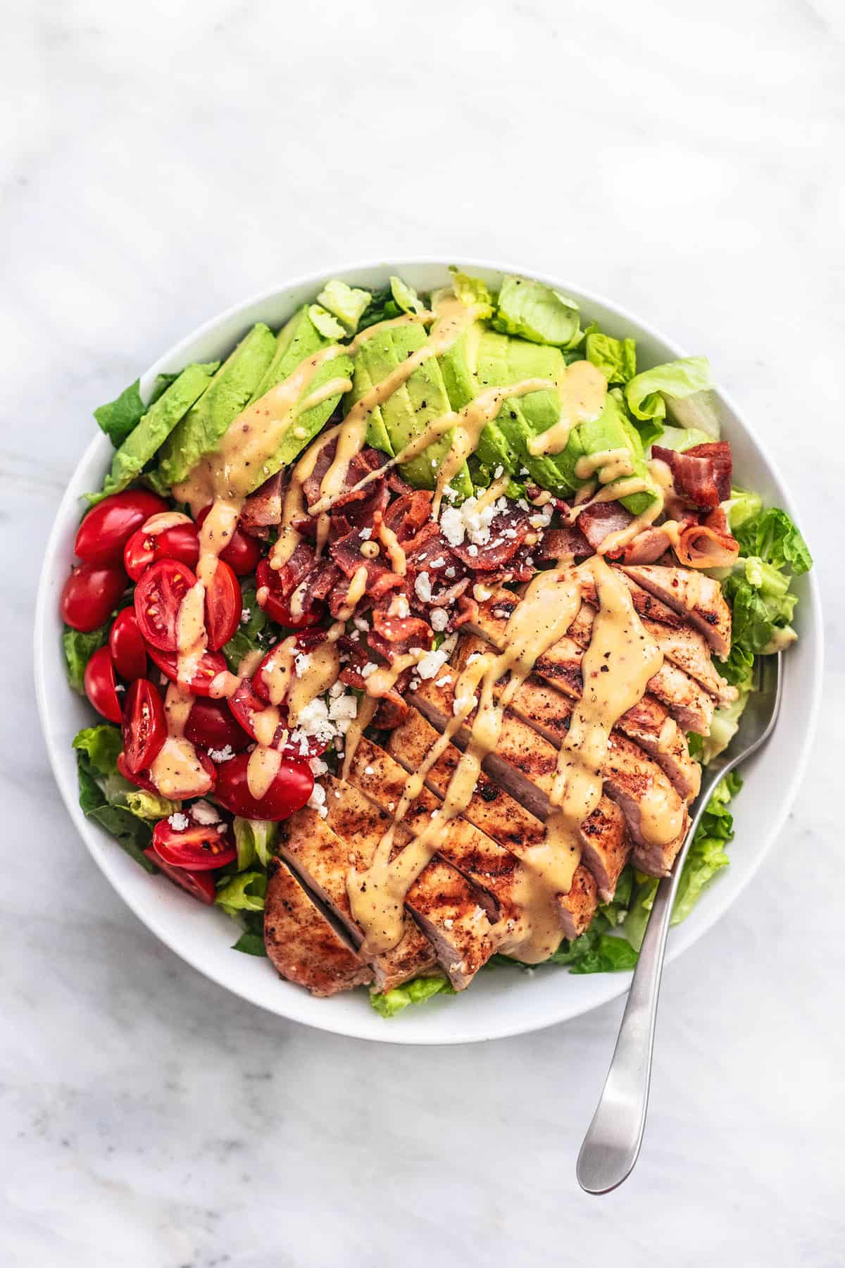 top view of chicken avocado salad with a fork on a plate.