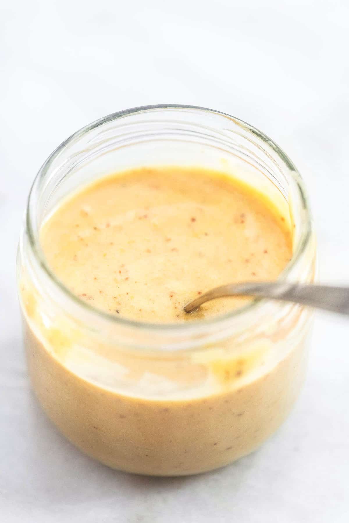 fat free Dijon salad dressing with a spoon in a glass.