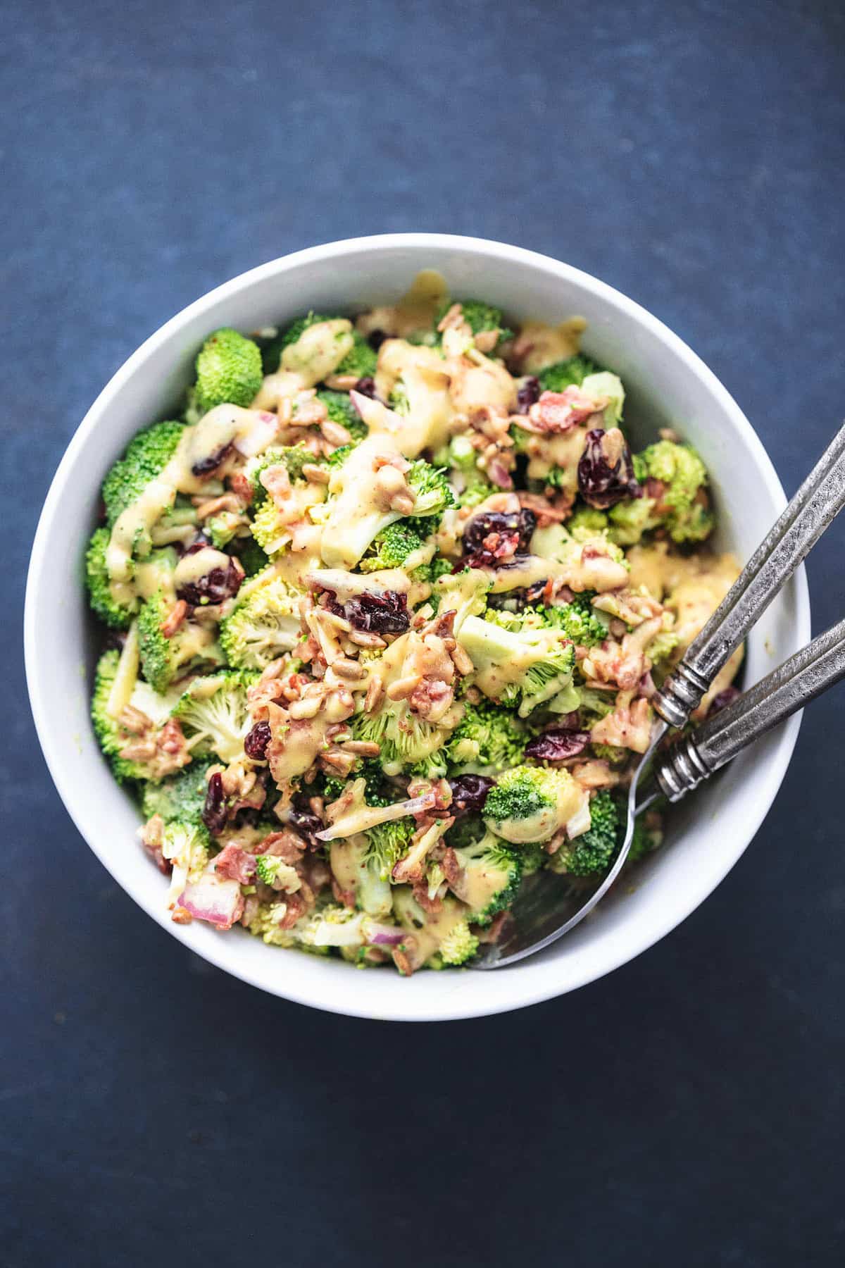 top view of broccoli salad with two spoons in a serving bowl.