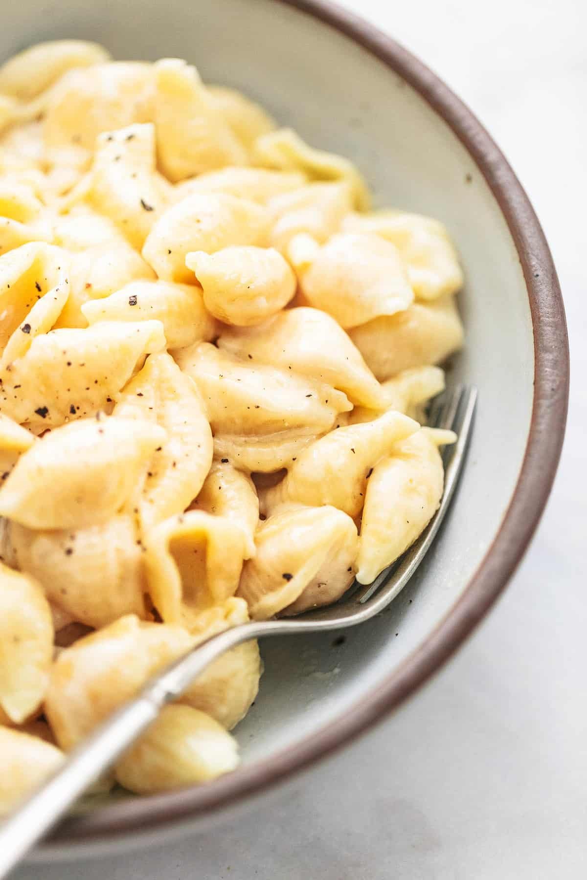 close up of instant pot mac and cheese with a fork in a bowl.