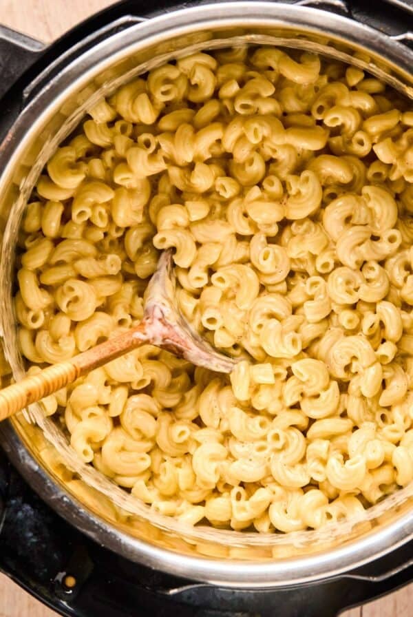 Overhead of instant pot mac and cheese with a wooden spoon in an instant pot.