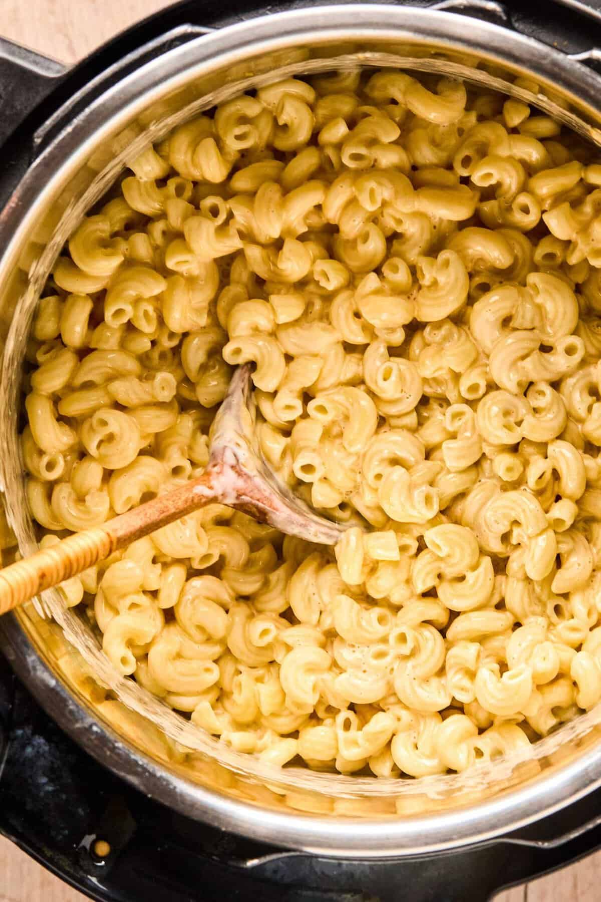 Overhead of instant pot mac and cheese with a wooden spoon in an instant pot.
