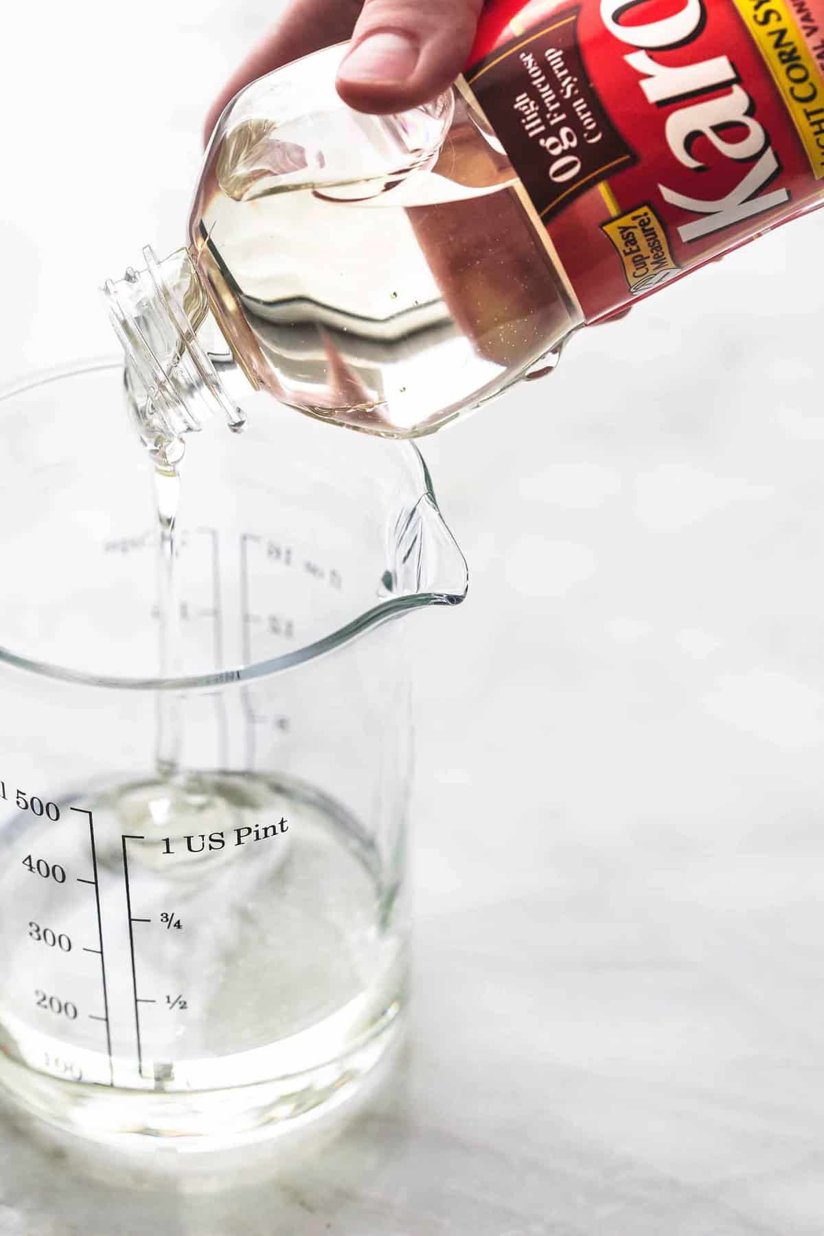 a Karo bottle of corn syrup being poured into a liquid measuring cup.