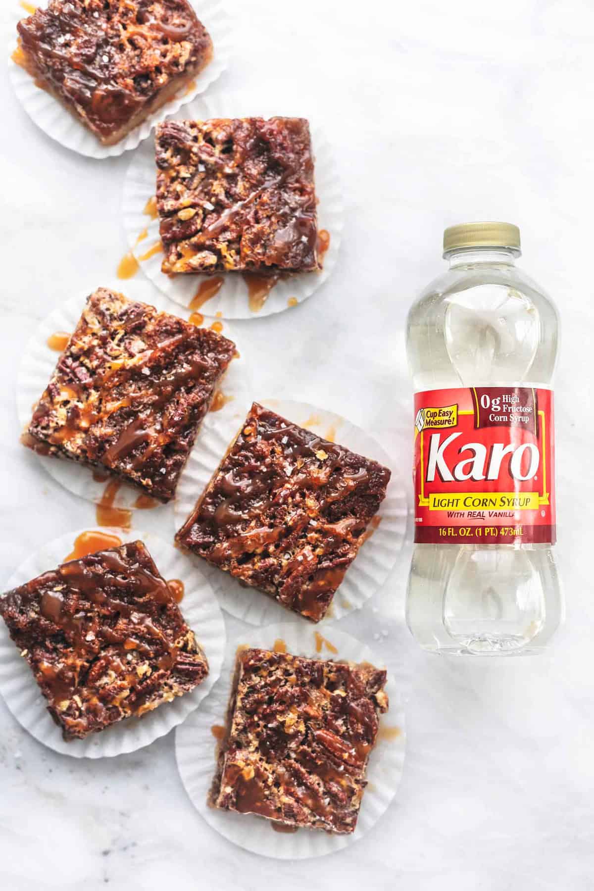 top view of salted caramel pecan pie bars on cupcake liners with a bottle of Karo corn syrup on the side.