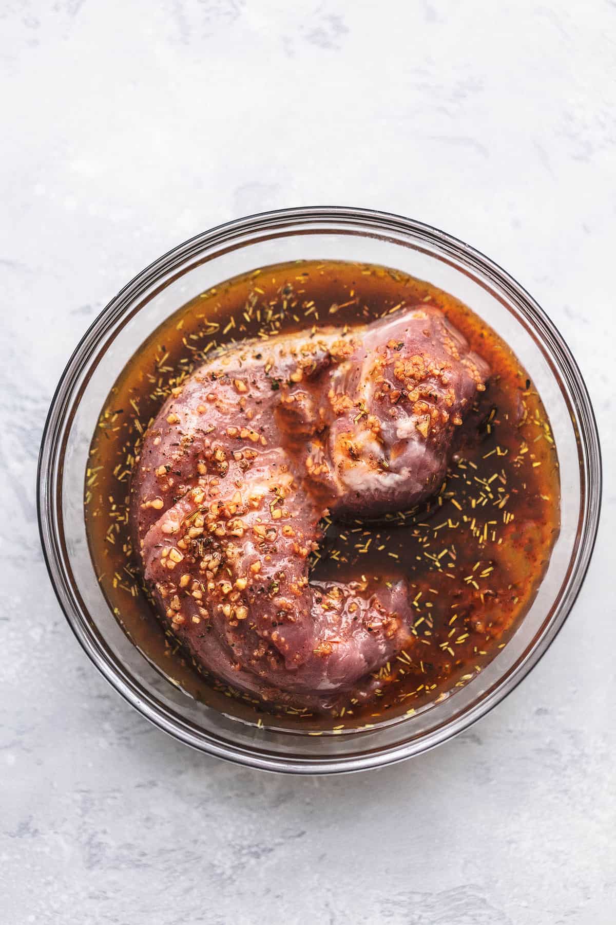top view of raw pork in pork marinade in a glass bowl.