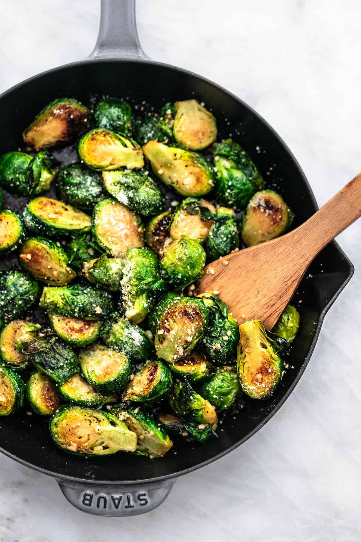 top view of sautéed brussels sprouts with a wooden spoon in a pan.