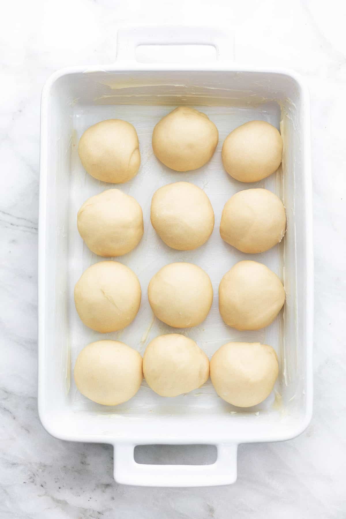 top view of unbaked potato rolls in a baking pan.