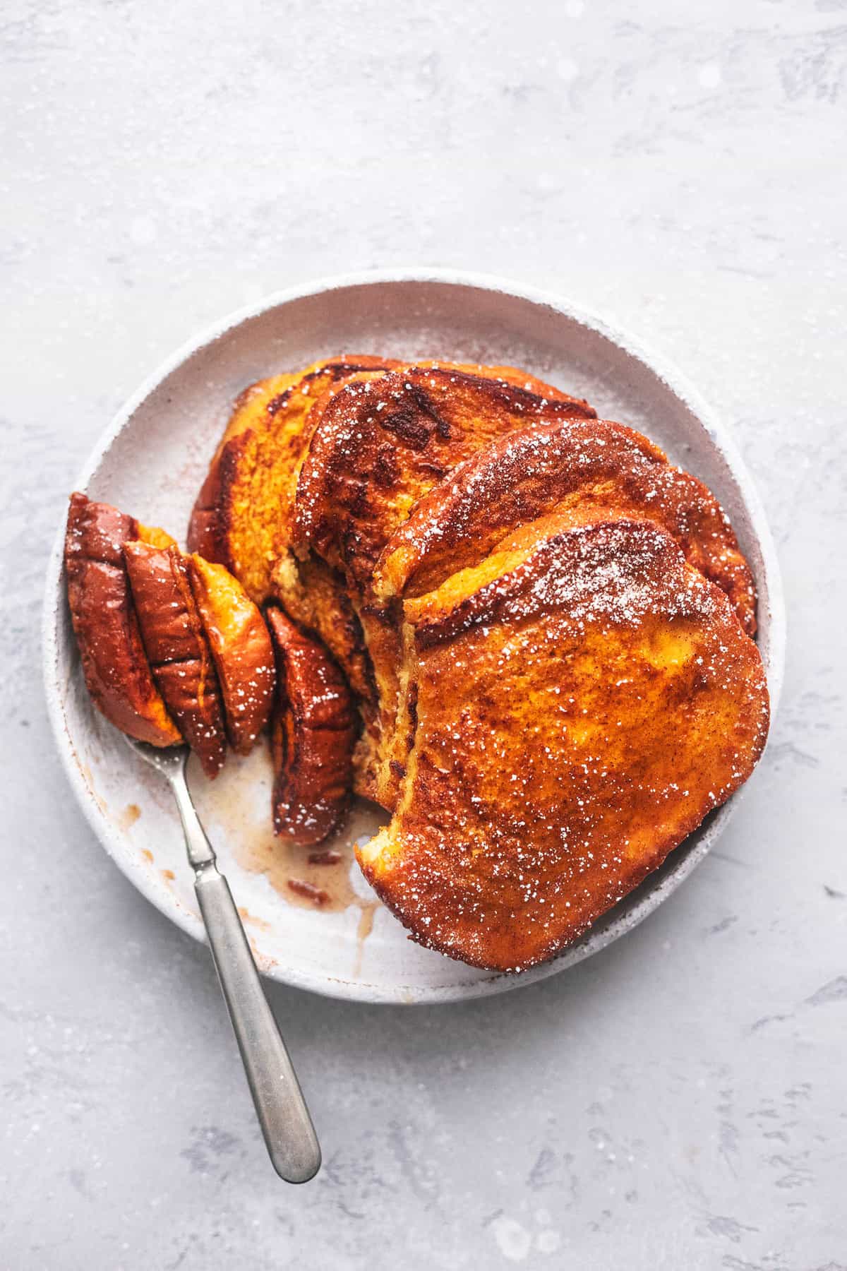 top view of stacked pumpkin French toast with a bite missing with the bite on a fork both on the plate.