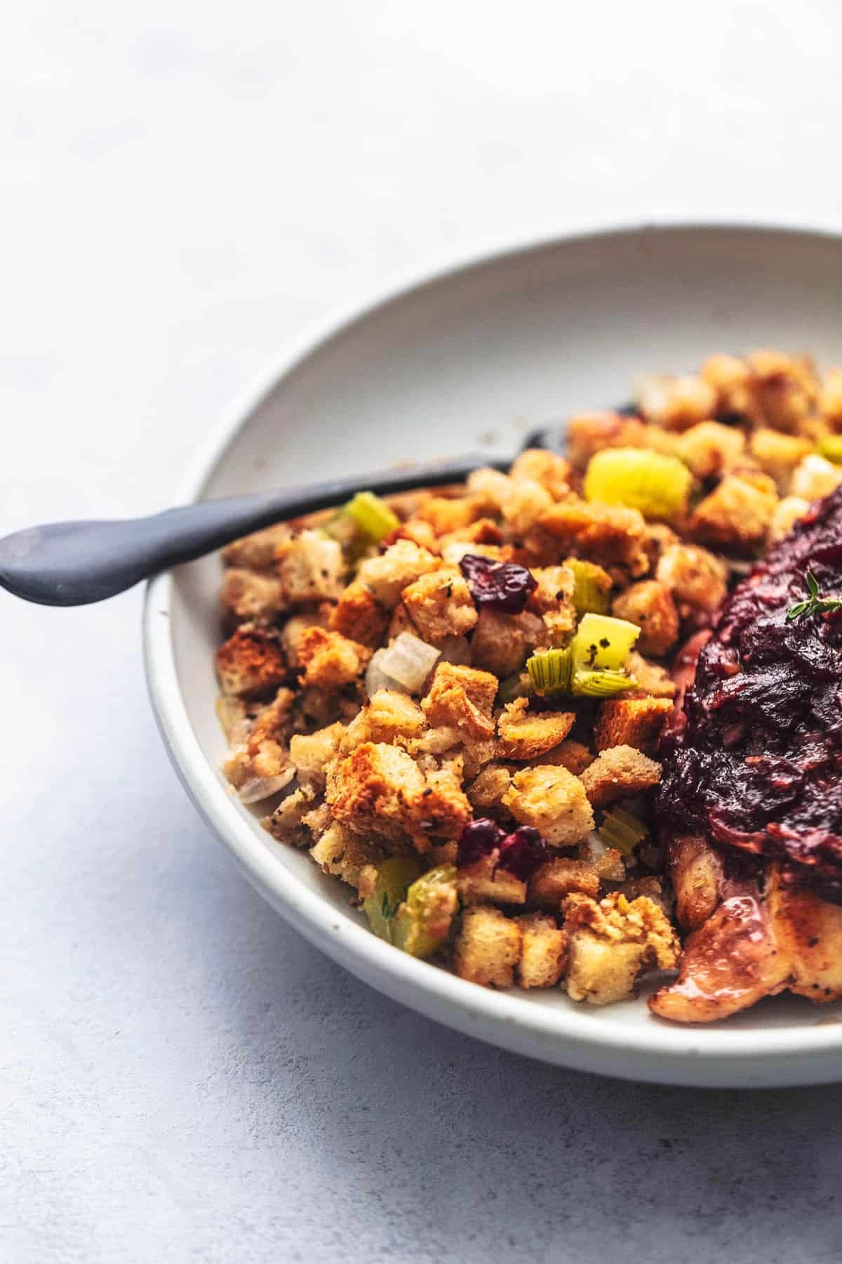 close up of sheet pan cranberry chicken and stuffing with a fork on a plate.