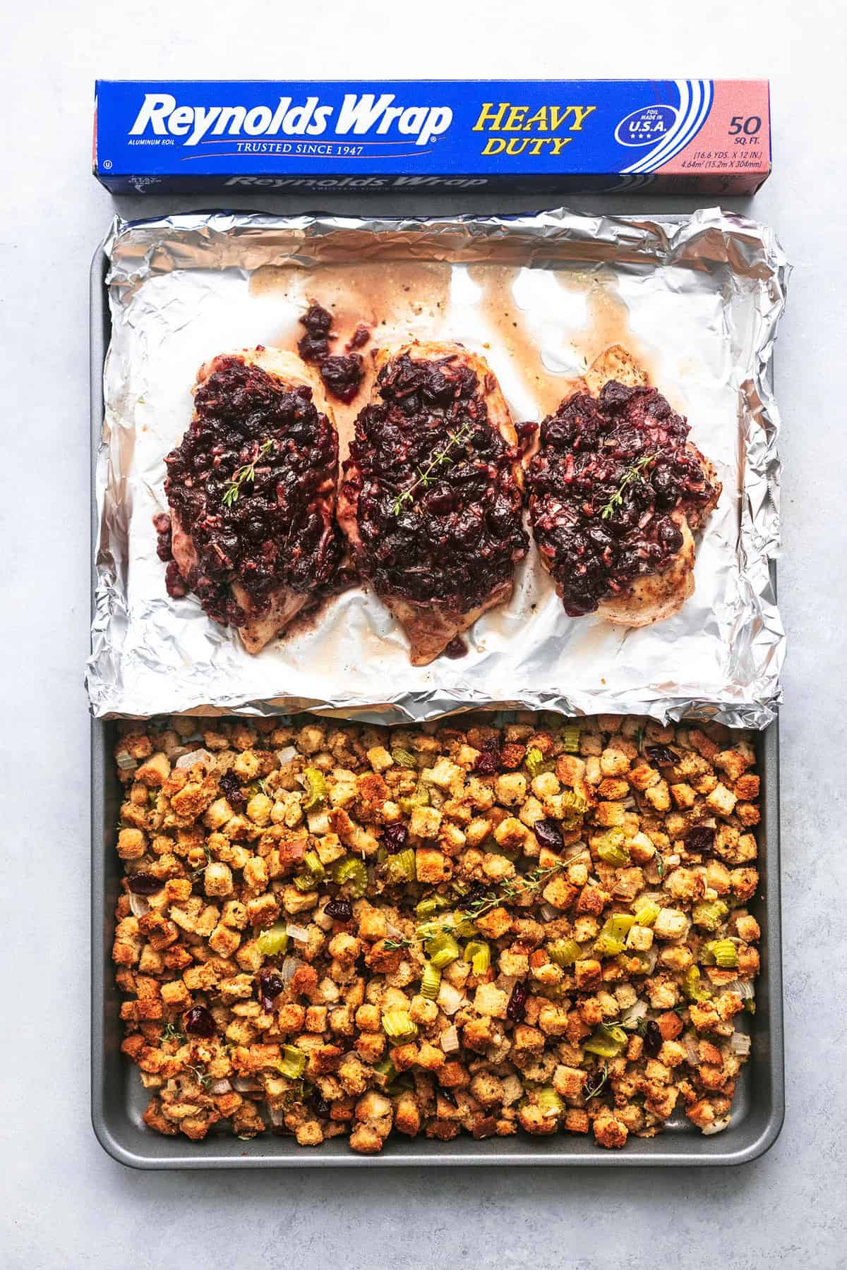 top view of sheet pan cranberry chicken and stuffing on a sheet pan with a box of Reynolds Wrap above the pan.