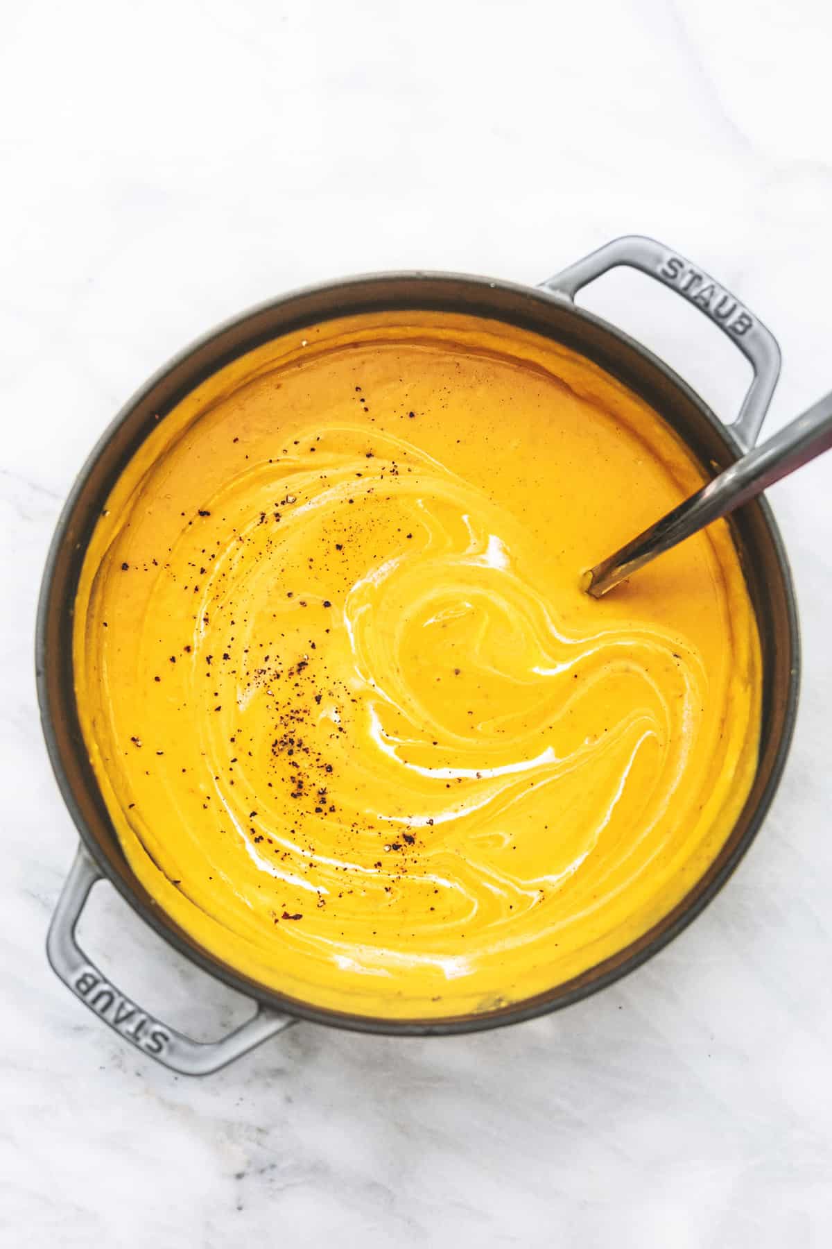 top view of creamy butternut squash soup with a serving spoon in a pot.