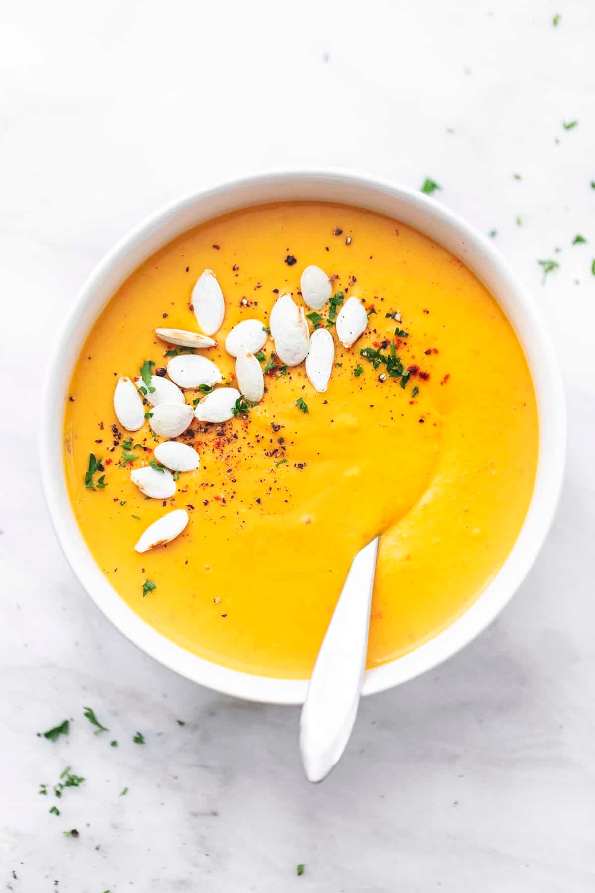 top view of creamy butternut squash soup with a spoon in a bowl.