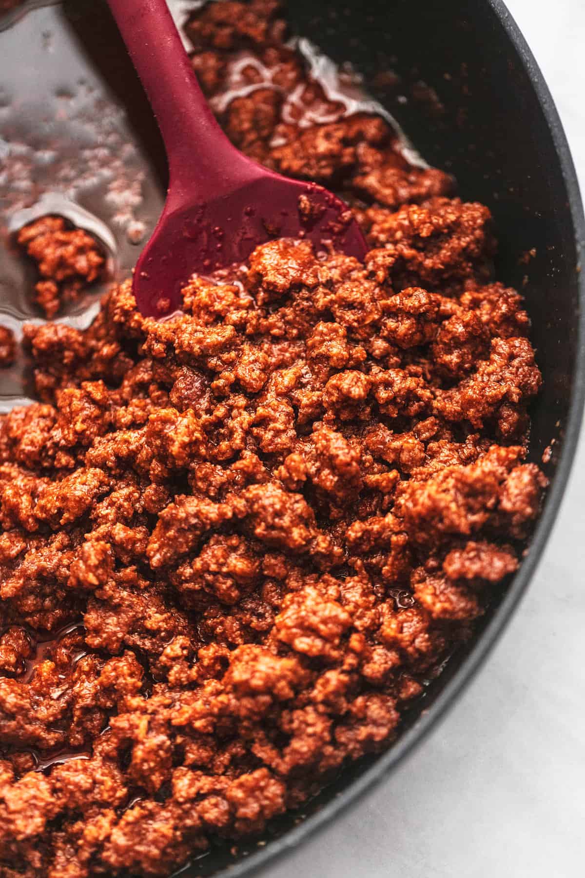 close up top view of ground beef with a spatula in a pan.