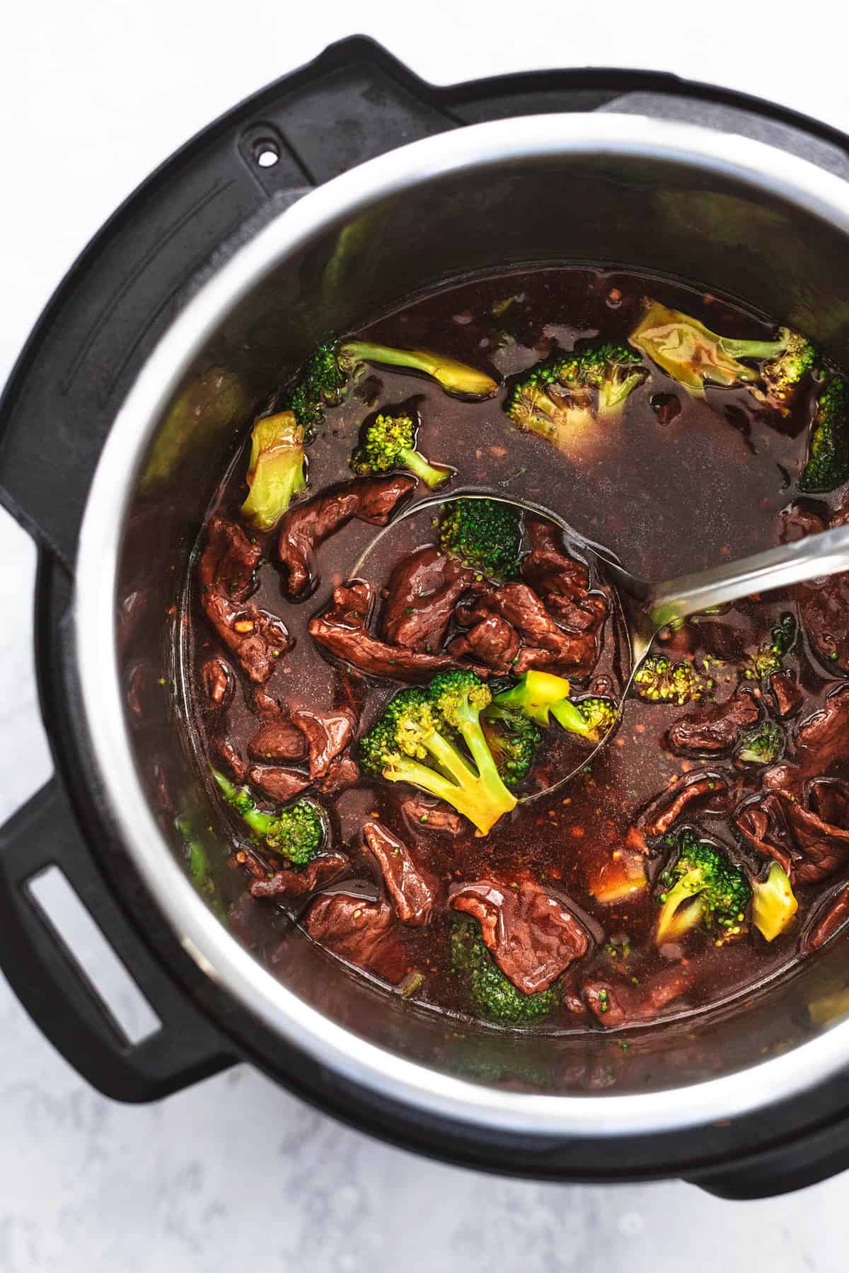 top view of broccoli and beef with a serving spoon in pressure cooker.