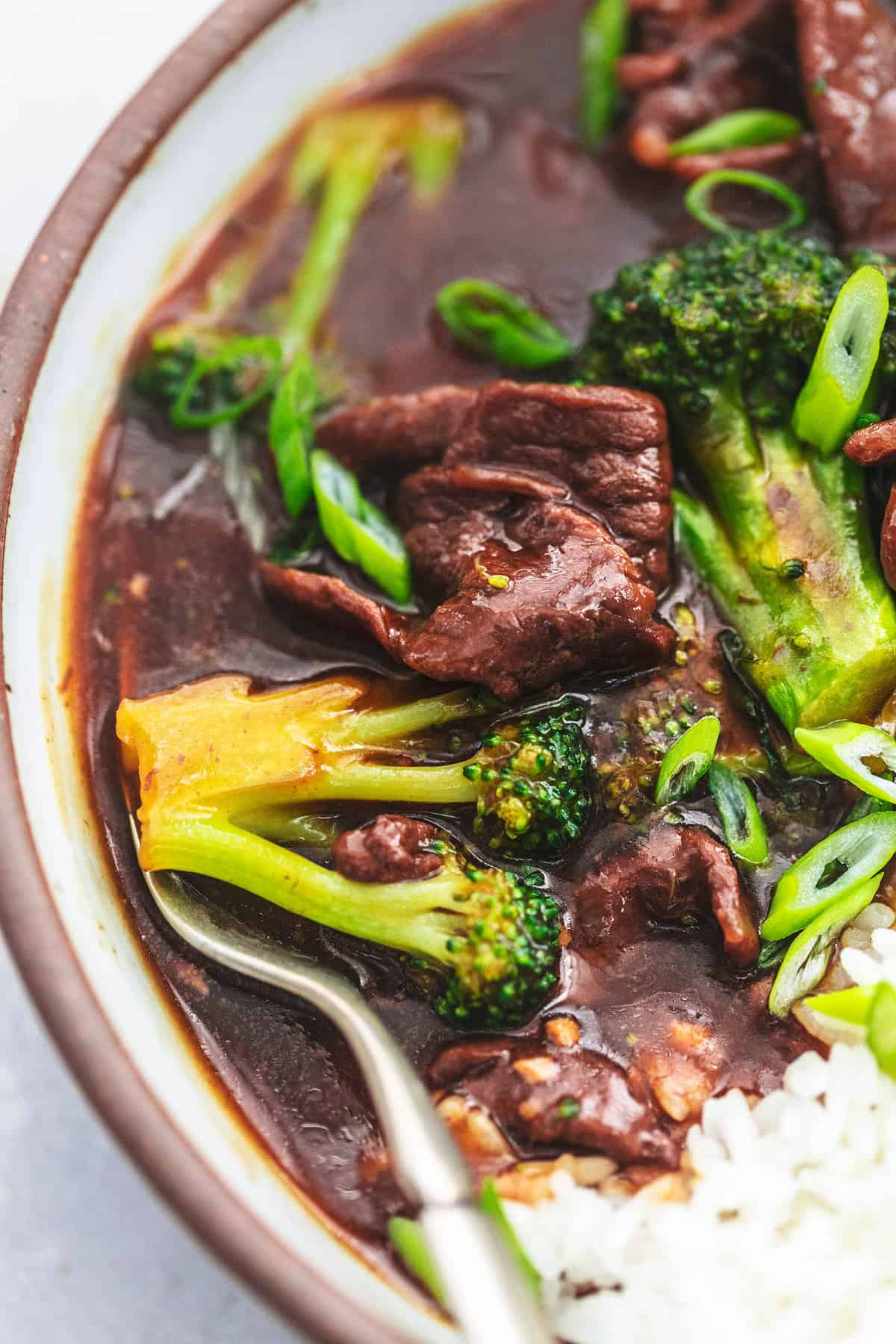 close up of broccoli beef in bowl with a fork.
