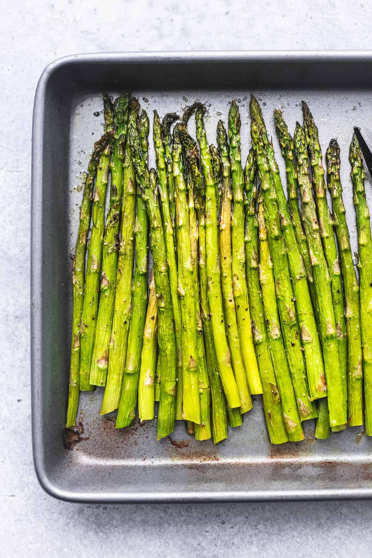 close up top view of roasted asparagus on a baking sheet.