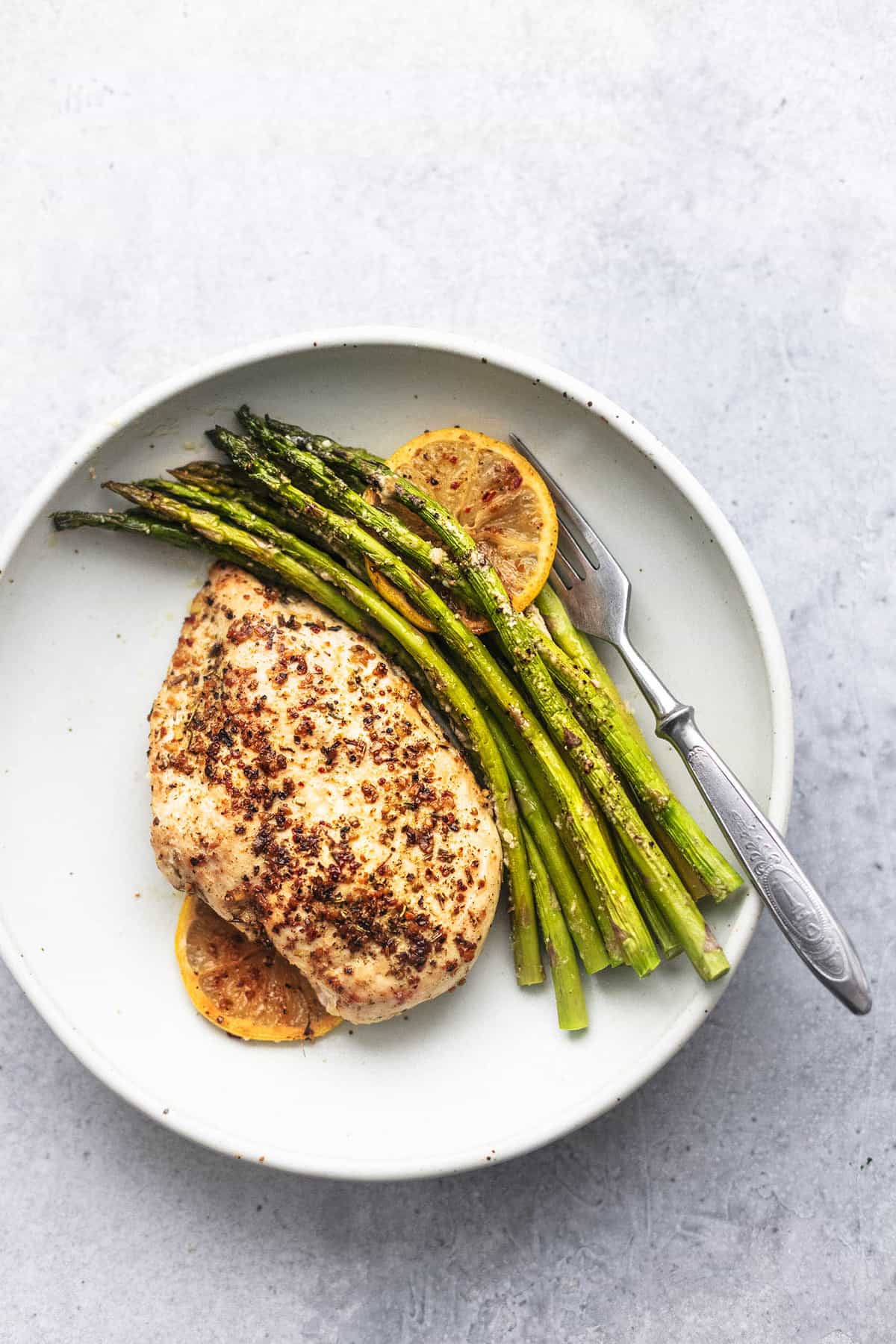 top view of sheet pan chicken and asparagus with a fork on a plate.