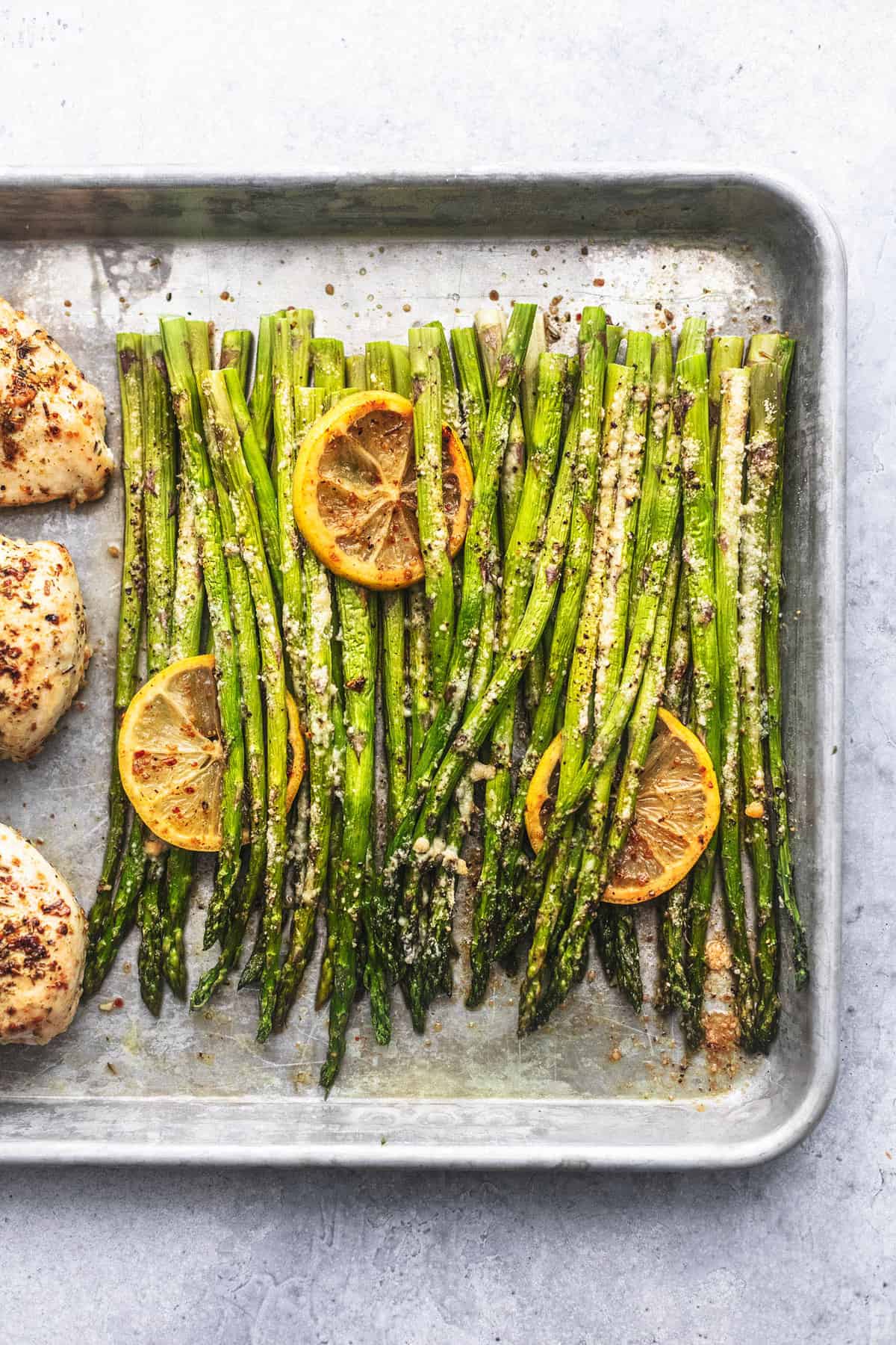 close up top view of asparagus and chicken barely visible on the side on a sheet pan.