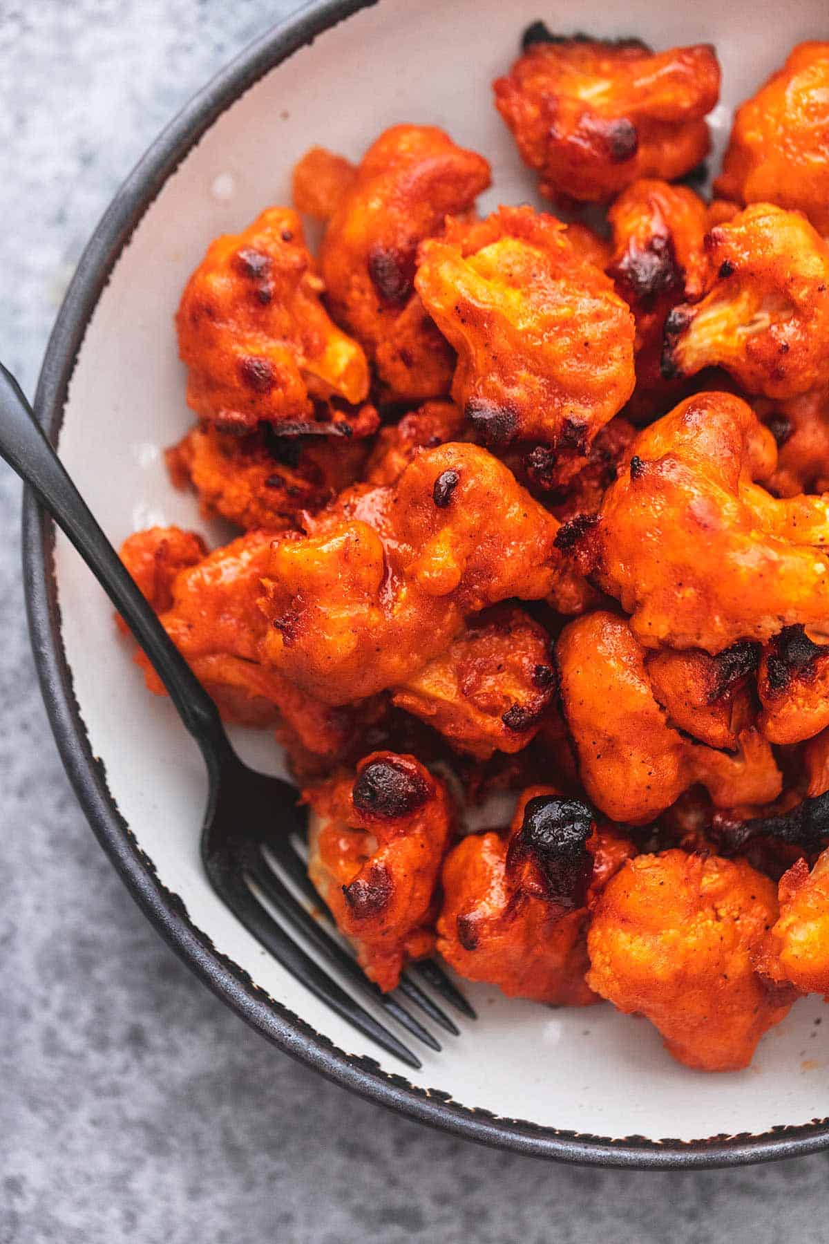 close up top view of buffalo cauliflower on a plate with a fork.