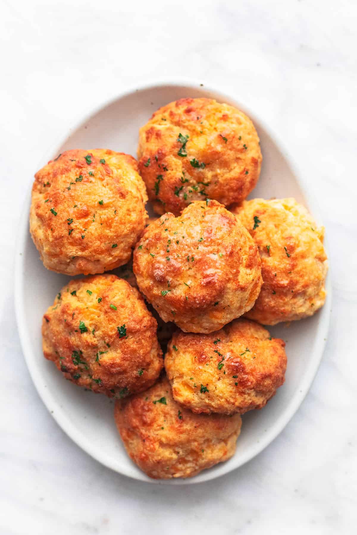 top view of red lobster cheddar bay biscuits on a white plate on marble background.
