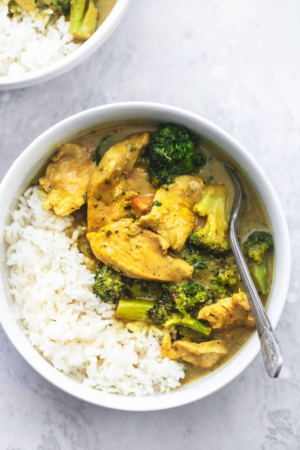 top view of chicken and broccoli coconut curry with a spoon in a bowl.
