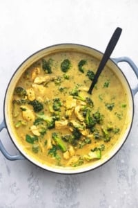 chicken and curry with broccoli in a pot with a spoon