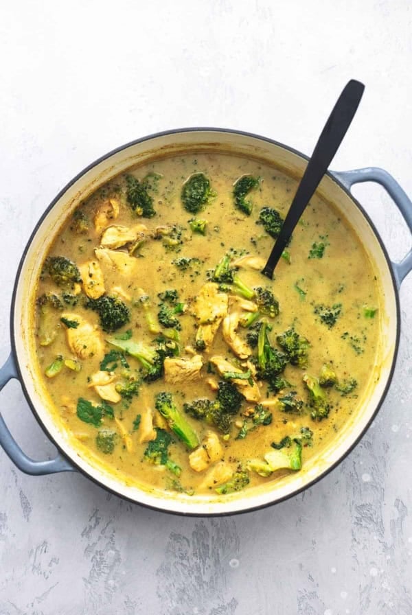 chicken and curry with broccoli in a pot with a spoon