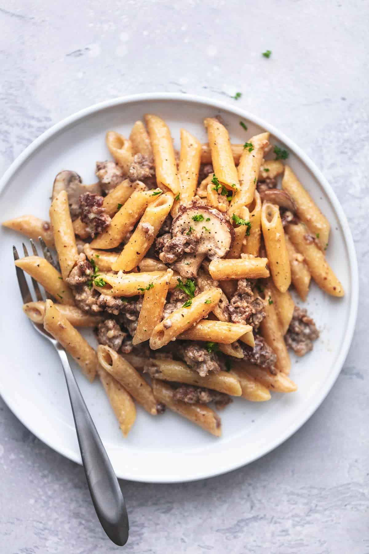 top view of creamy sausage pasta with a fork on a plate.