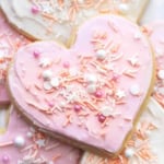 up close heart shaped sugar cookie with pink frosting and sprinkles