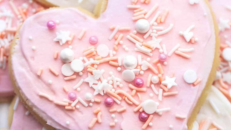 up close heart shaped sugar cookie with pink frosting and sprinkles