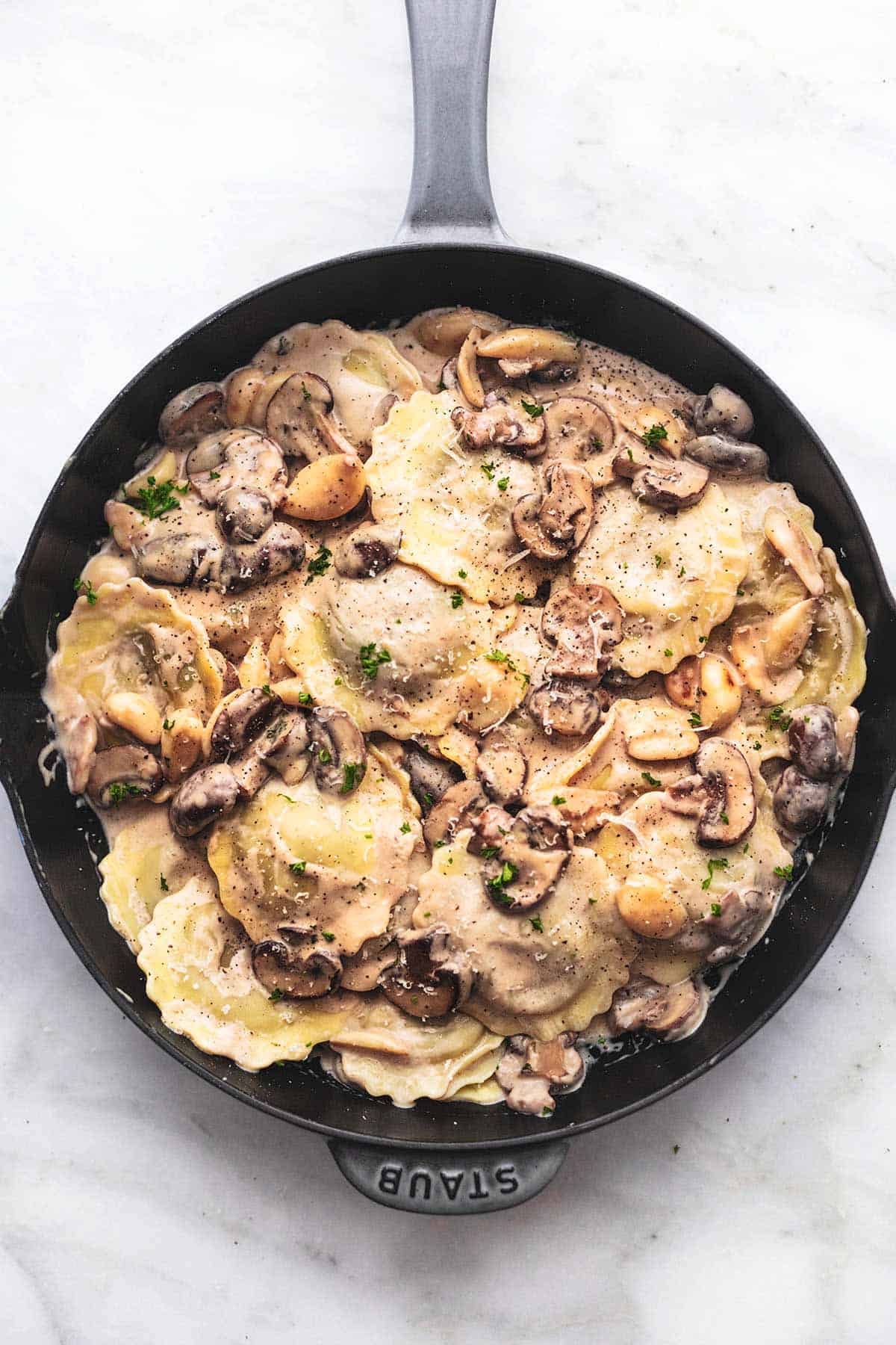 top view of ravioli with mushroom cream sauce in a skillet.