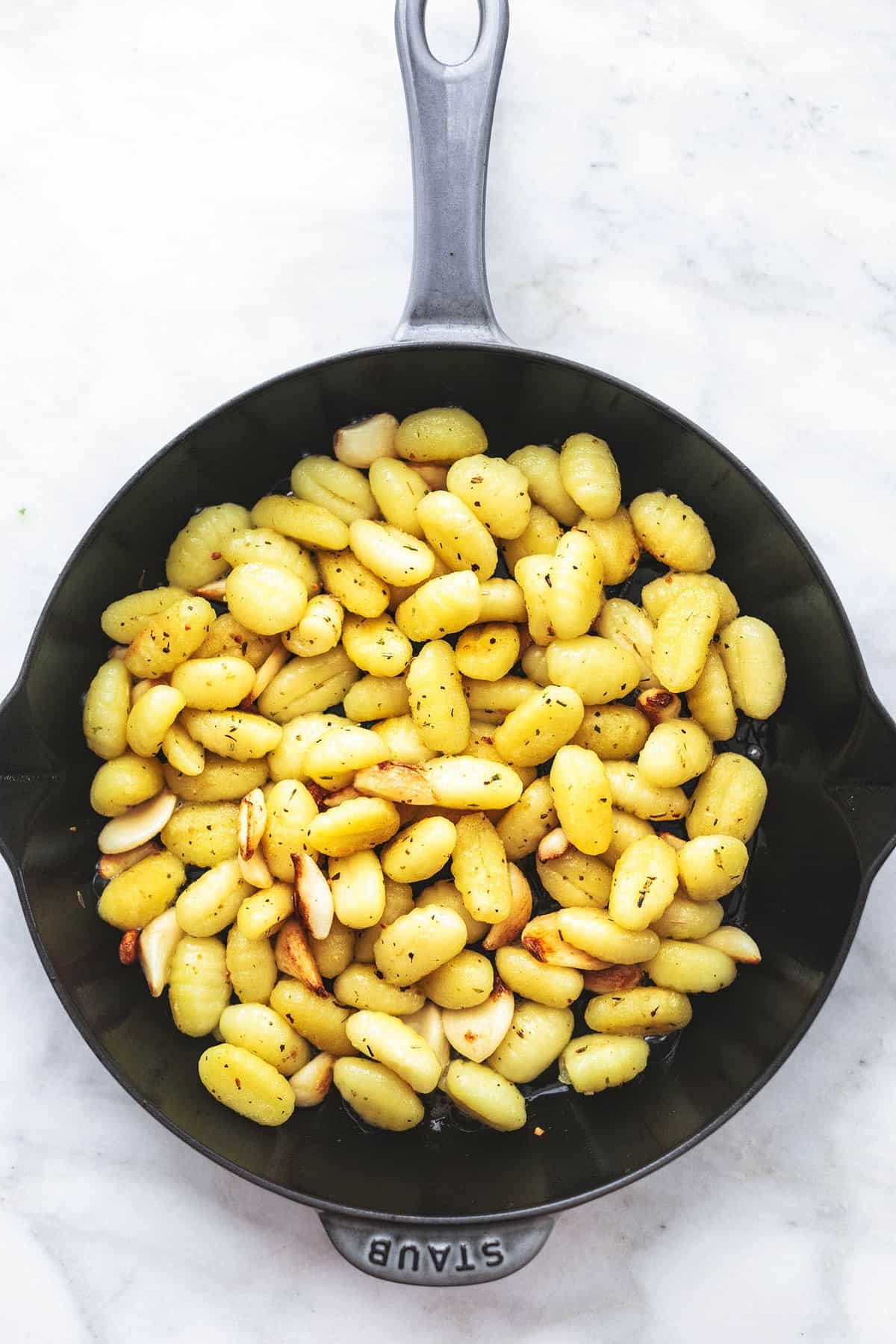 top view of buttery gnocchi and herbs in a skillet.