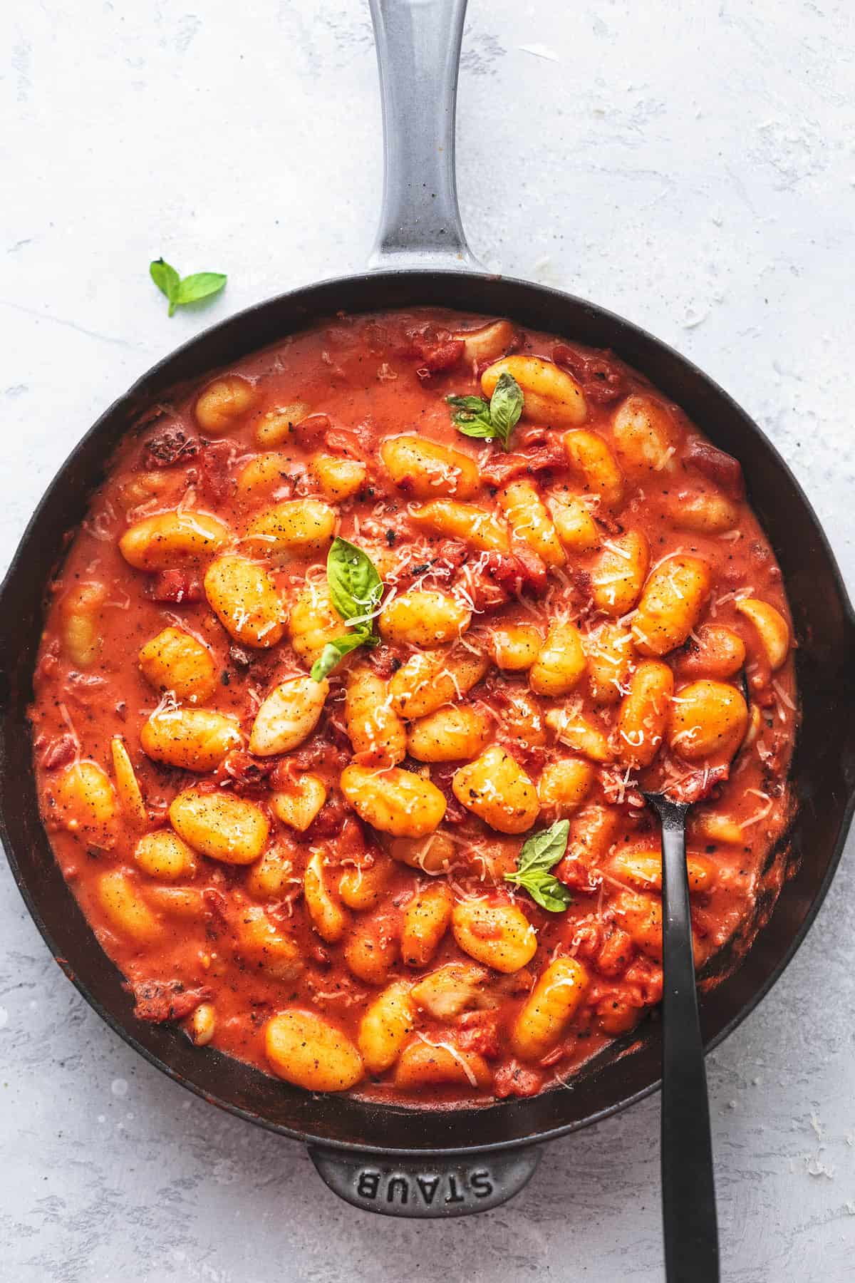 gnocchi with creamy tomato sauce and basil in a skillet with a spoon