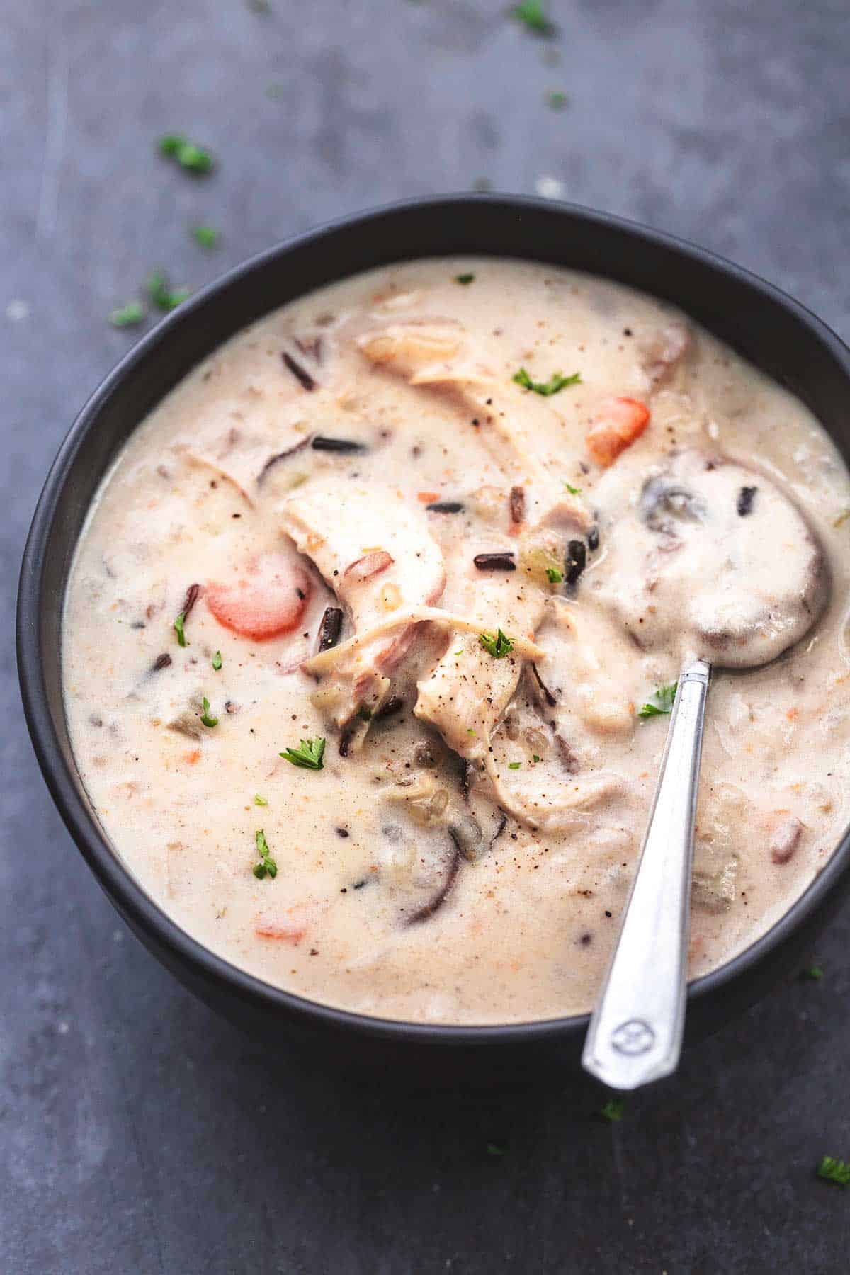 chicken and wild rice soup with spoon in black bowl.