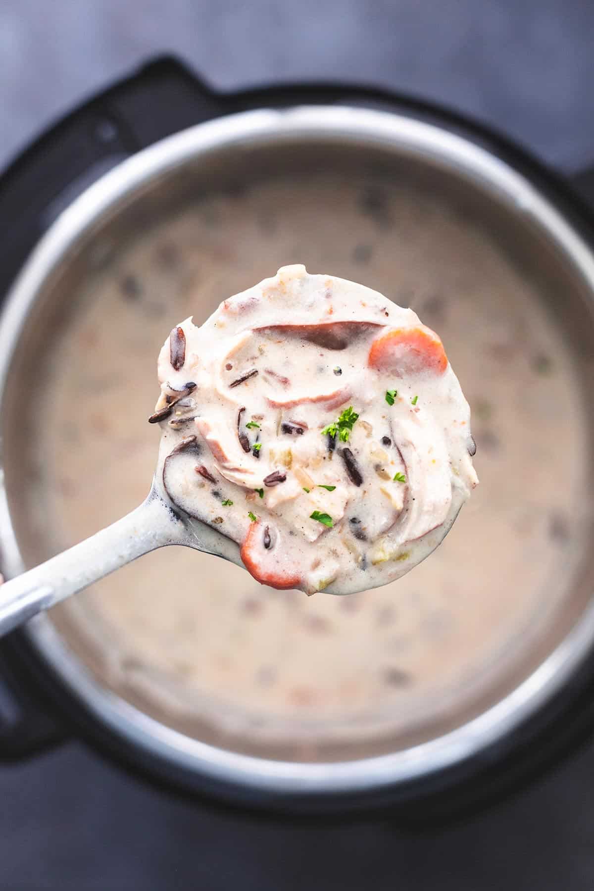 top view of a ladle of chicken and wild rice soup over an instant pot pressure cooker of more soup.