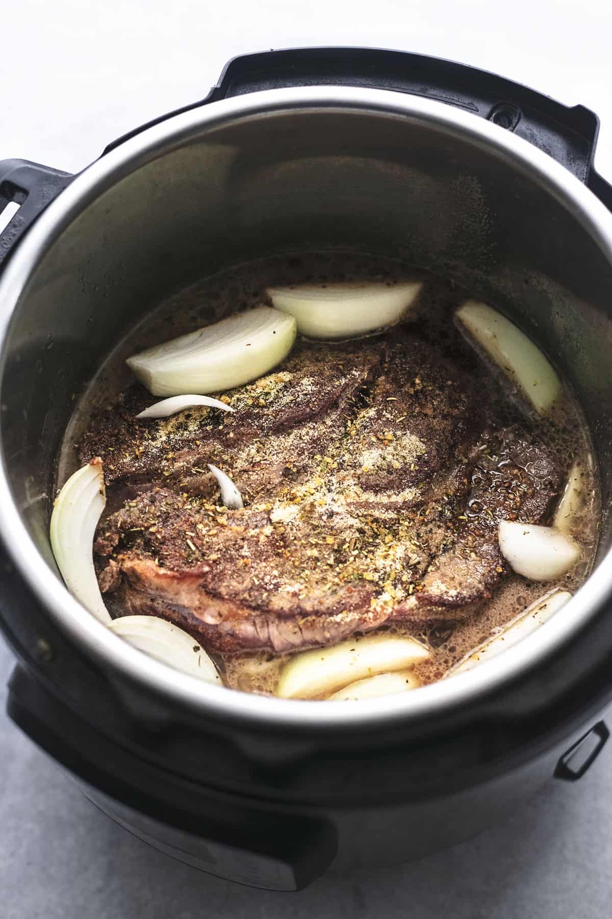 beef onions and seasonings in an instant pot for french dip sandwiches.