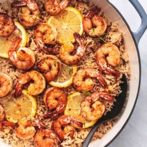 shrimp and rice with lemon slices in a skillet with a spoon